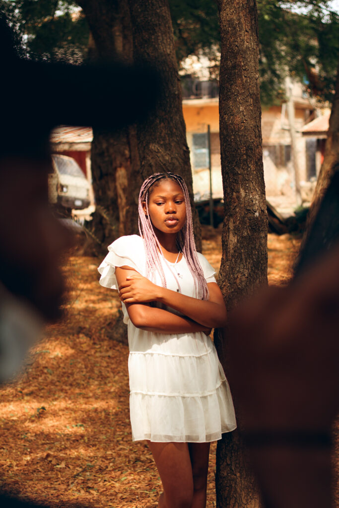 Young woman standing beside a tree